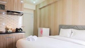 A hotel room with a bed, a small kitchenette, and a refrigerator. - Comfortable Fully Furnished Studio Green Pramuka City Apartment (Jakarta)