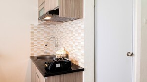 A compact kitchen with a microwave, sink, and a small coffee machine. - Comfortable Fully Furnished Studio Green Pramuka City Apartment (Jakarta)