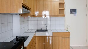 Keittiössä on puukuvioiset kaapit, valkoisilla laatoilla päällystetty seinäosa, ruostumattomasta teräksestä valmistettu pesuallas ja musta työtaso.