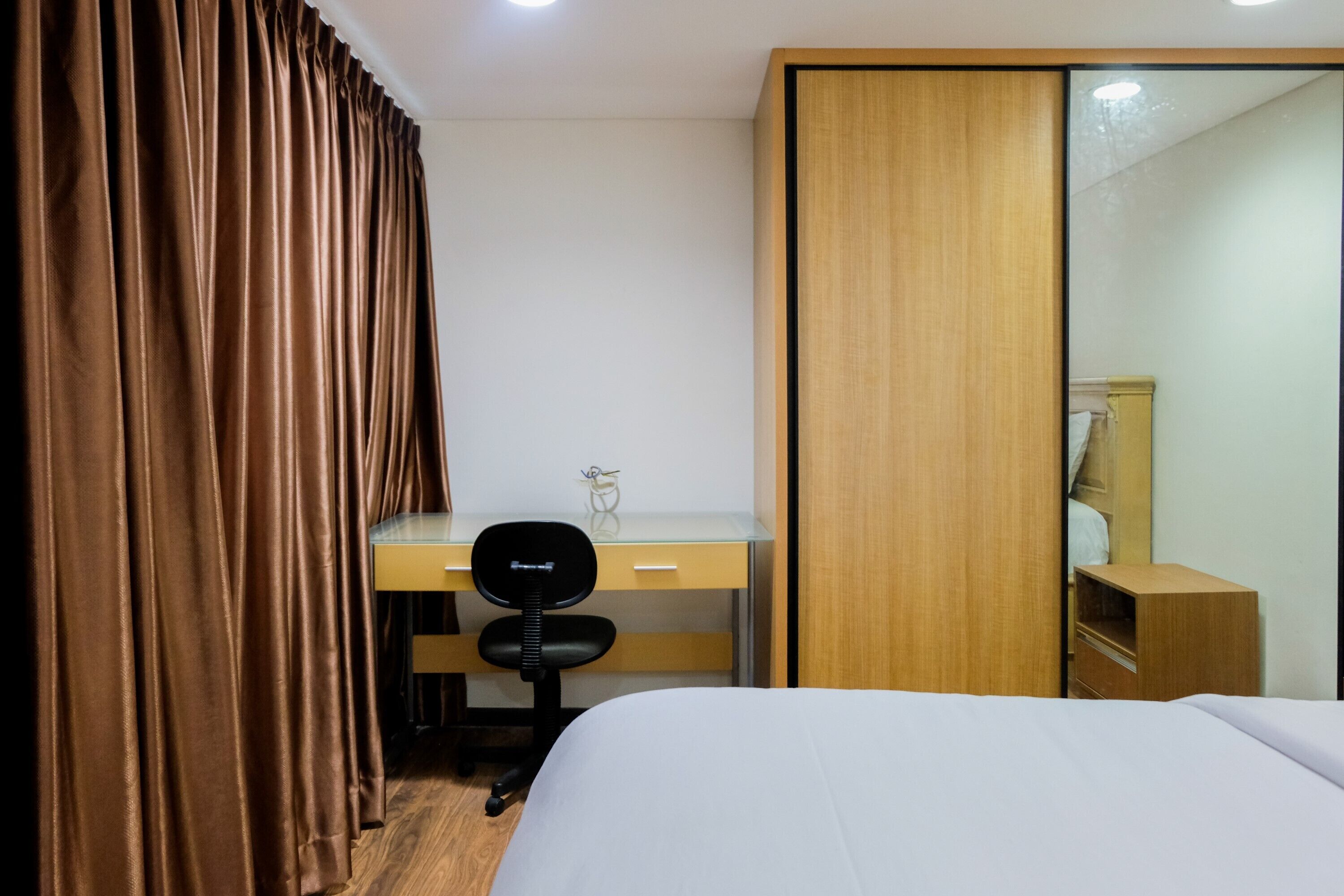 A hotel room with a bed, a desk, a chair, and a wardrobe.