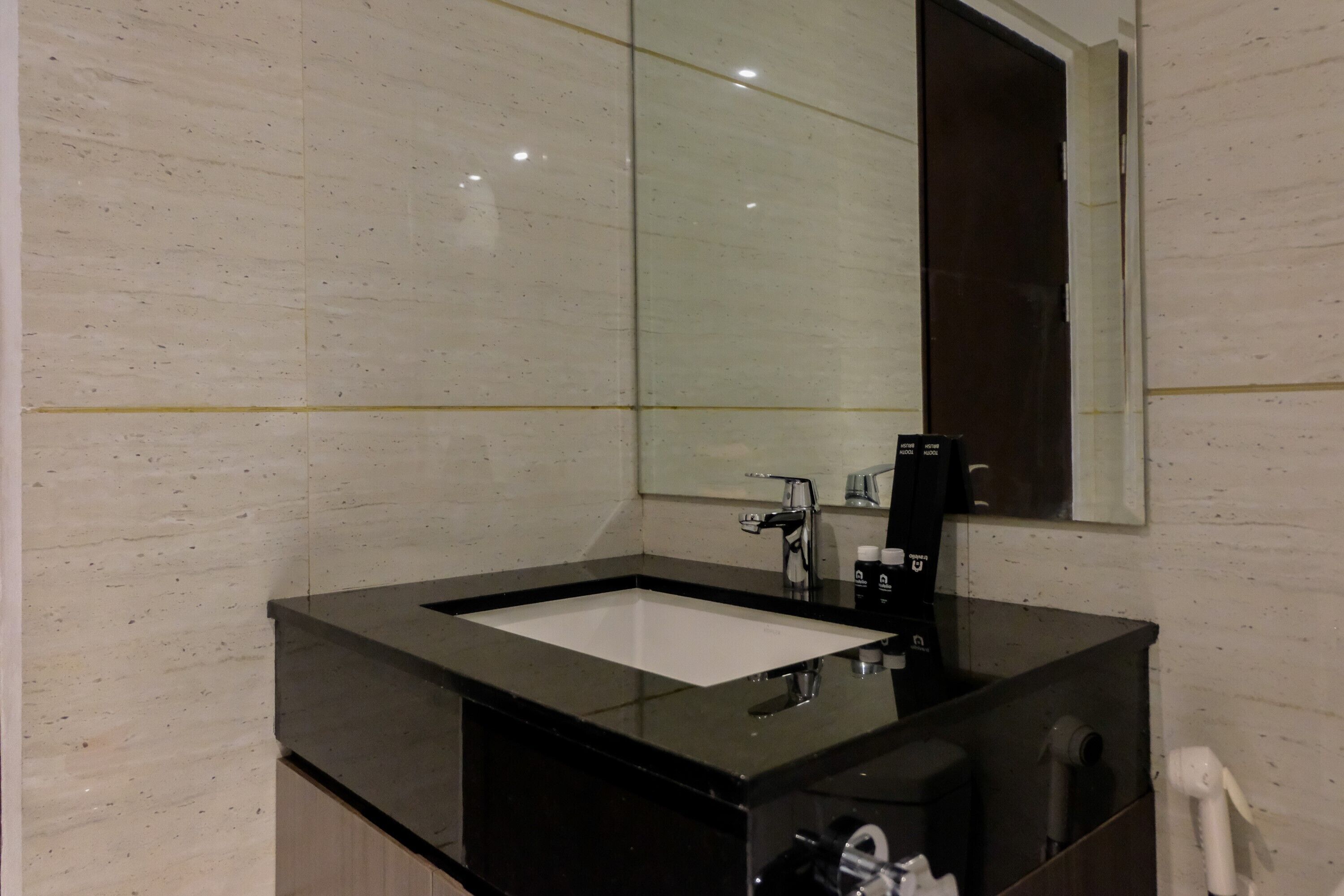 A modern bathroom with a black sink, a large mirror, and a white tiled wall.
