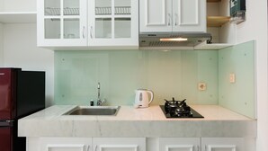 Eine moderne Küche mit weißen Schränken, einer Edelstahl-Spüle, einem Gasherd und einem eingebauten Backofen.