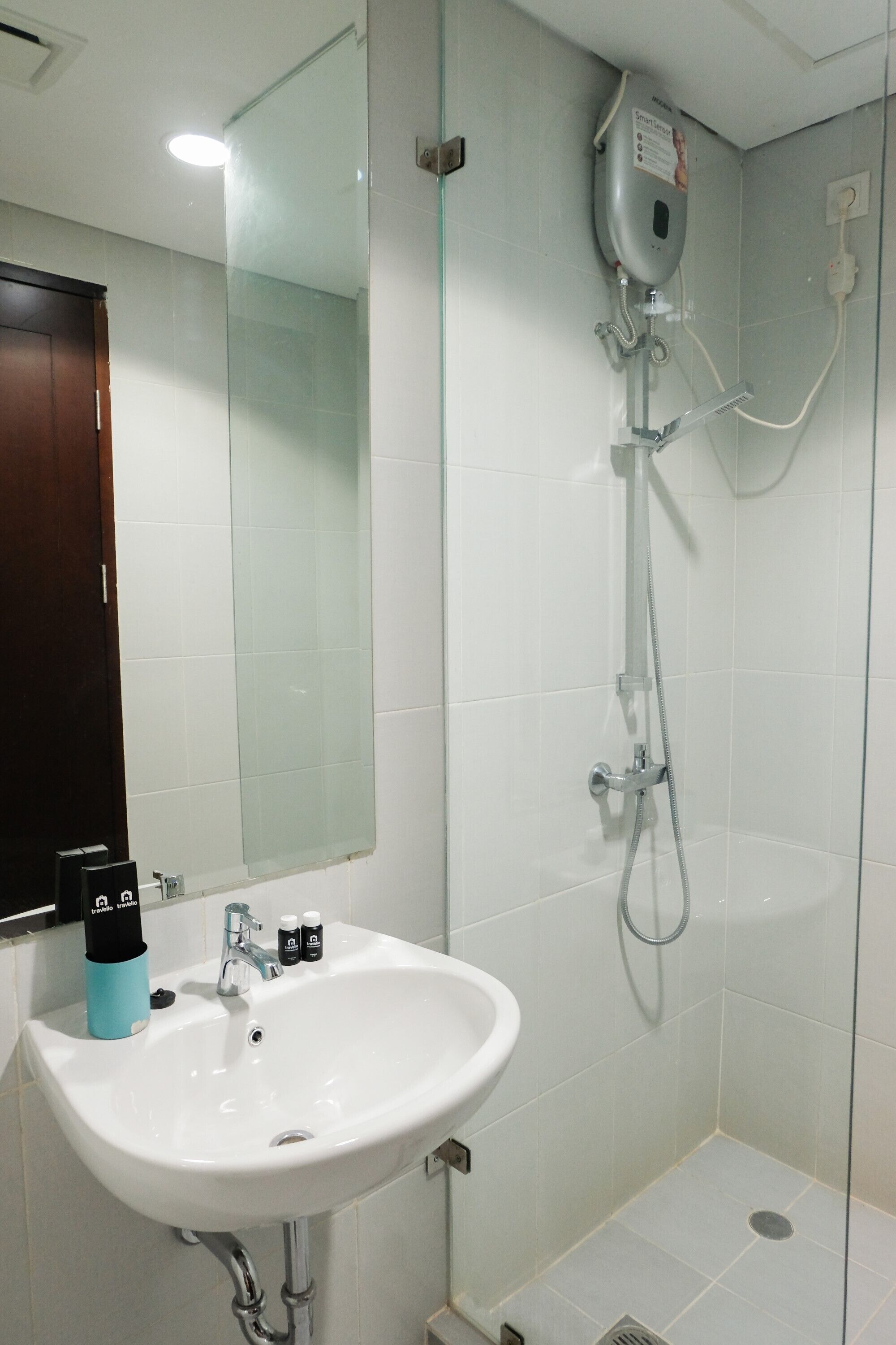 Un baño con un lavabo blanco, cabina de ducha con mampara de vidrio y un espejo.