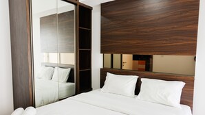 Une chambre d’hôtel avec un grand lit, une tête de lit en bois, un miroir et une armoire.