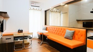 Une chambre d’hôtel moderne équipée d’un canapé, d’une petite table, d’une télévision et d’un miroir.