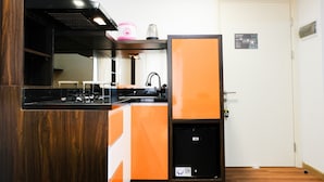 Une cuisine compacte équipée d’une cuisinière intégrée, d’un évier et d’un petit réfrigérateur.