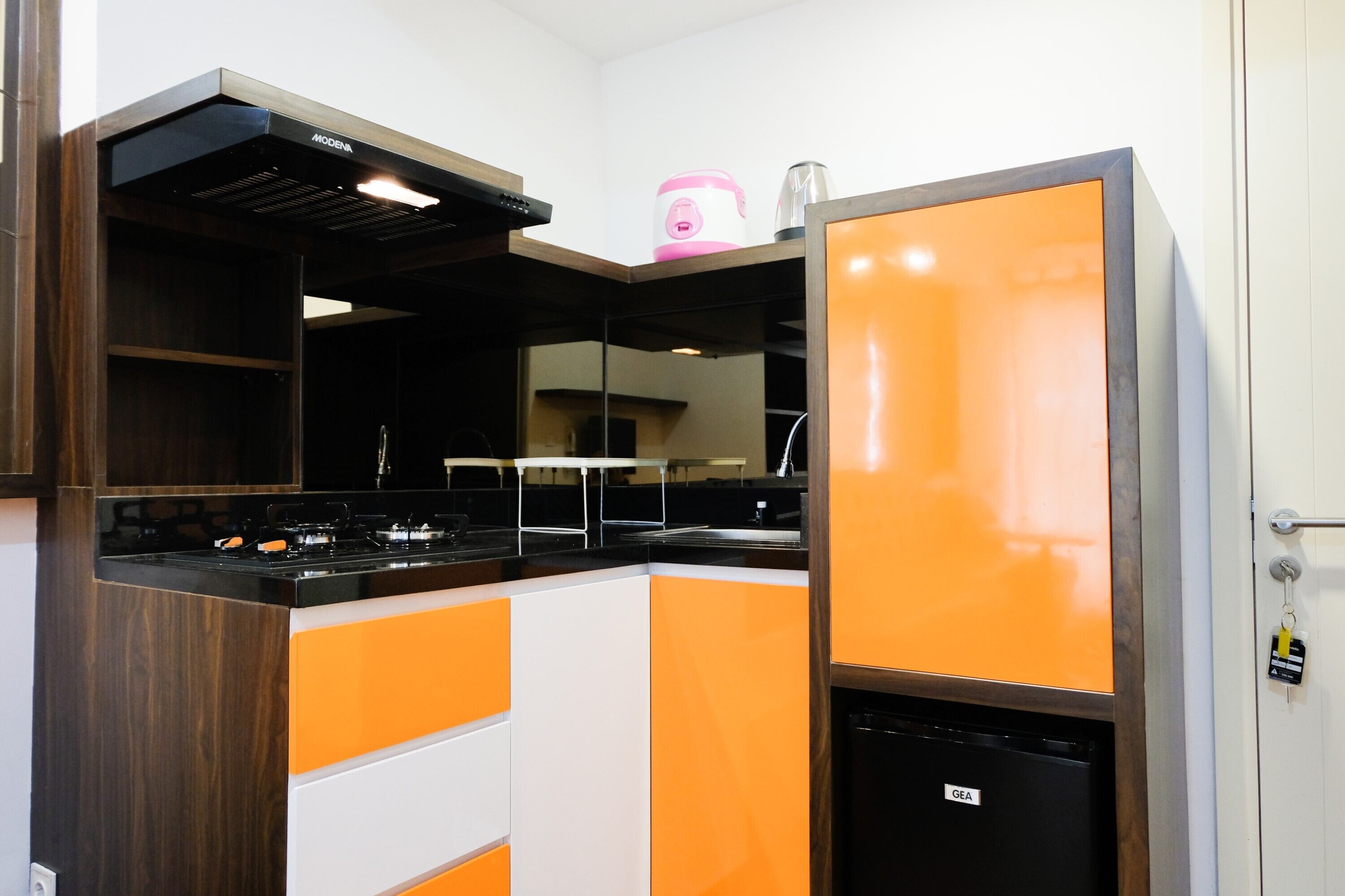 A modern kitchen with a built-in stove, a compact refrigerator, and a microwave.