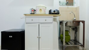 A compact kitchen with a GEA refrigerator, a white cabinet with two doors, a countertop with a rice cooker, a toaster, and a sink with a faucet. - Studio near Bella Terra Mall at Tifolia Apartment (Jakarta)