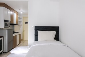 Cozy retreat with a bed and kitchenette area, featuring a microwave, stove, and refrigerator.