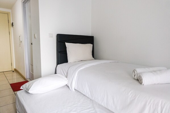 Comfortable bed with a simple, functional design and a cozy red rug at the foot.