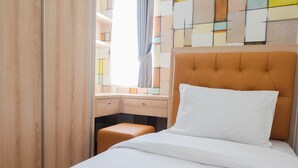 Ein Hotelzimmer mit Bett, einem Holzschrank, einem Schreibtisch und einem Fenster mit Vorhängen.