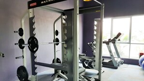 Ein Fitnessraum mit Kraftstation, Laufband und Fenster mit Blick ins Freie.
