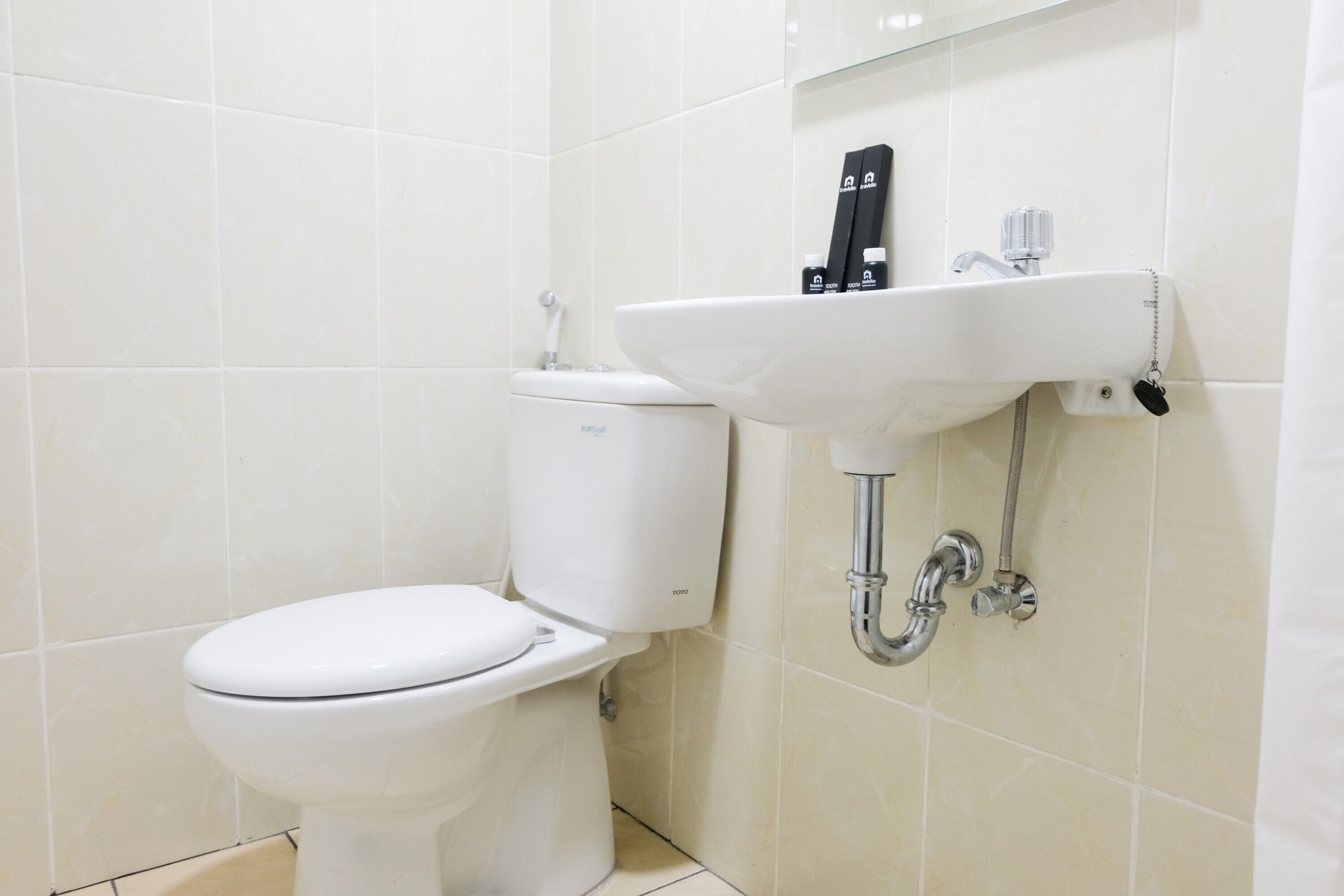 Un baño con inodoro blanco, lavamanos y espejo.