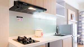 Une cuisine moderne avec un plan de travail blanc, une hotte noire, un grille-pain blanc et un évier en acier inoxydable.