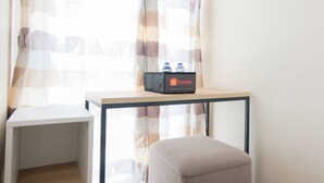 Une petite pièce propre, avec une table en bois, un banc et un sac de voyage posé sur la table.