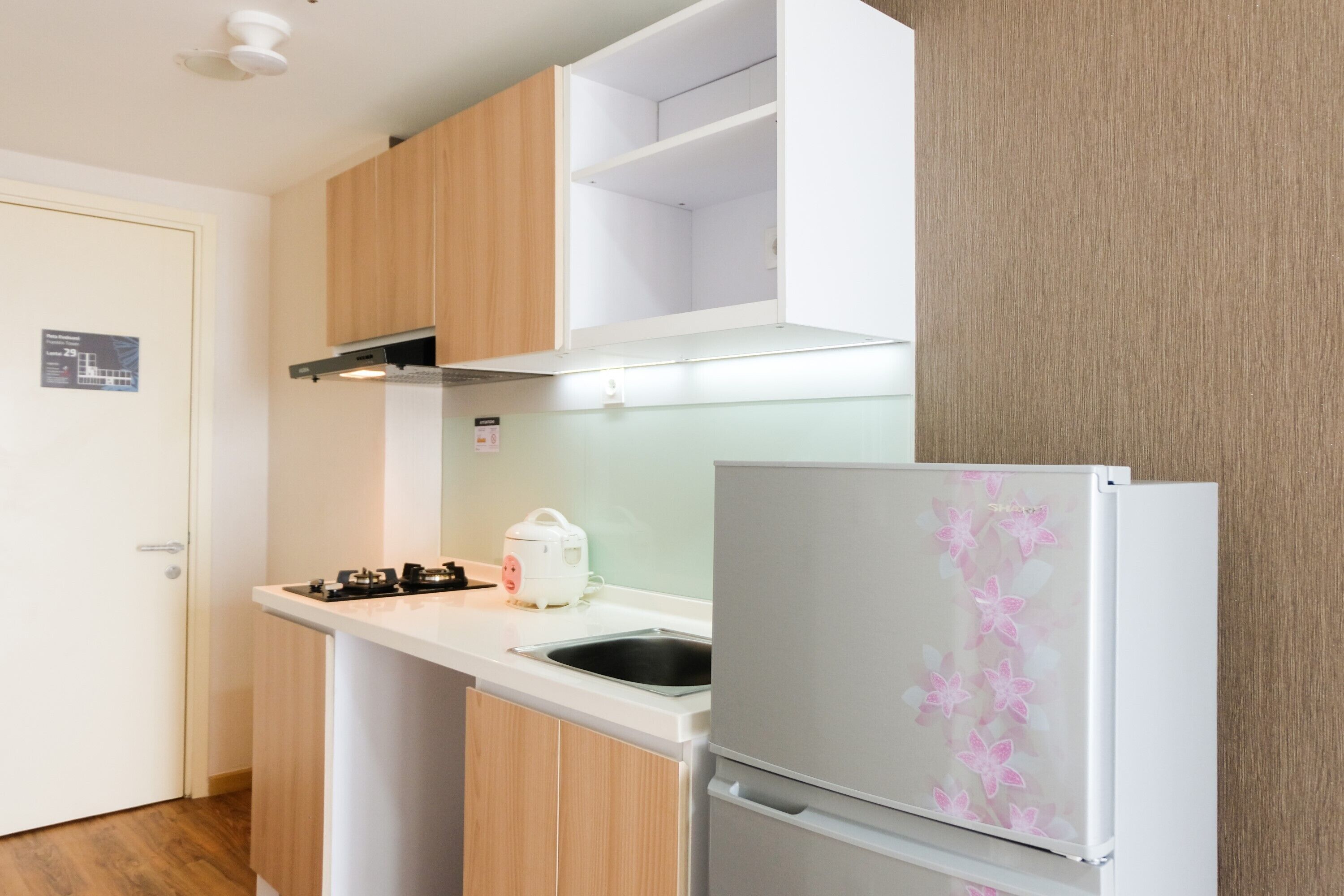 A kitchen with wooden cabinets, a white countertop, a sink, a stove, and a refrigerator with a floral design.
