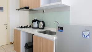 A compact kitchen with a built-in gas stove, a coffee maker, and a stainless steel sink. - Comfortable Studio Apartment M-Town Residence (Gading Serpong)