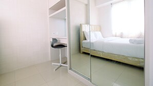 A modern hotel room with a glass partition, a bed, a desk, and a chair. - Best Price 2BR Bassura City Apartment (Jakarta)