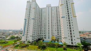 A high-rise residential building with multiple floors, a central courtyard with a pool, and surrounding greenery. - Best Price 2BR Bassura City Apartment (Jakarta)