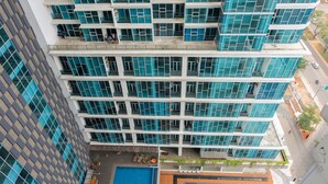 A high-rise building with multiple floors, large windows, and a rooftop pool area. - Cozy Studio Apartment at Brooklyn Alam Sutera (South Tangerang)
