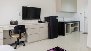 A modern kitchen with a flat-screen TV, a refrigerator, and a sink. - Modern City View Studio Apartment at Tuscany Residences (South Tangerang)