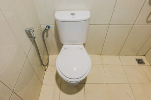 A standard white toilet with a bidet attachment in a tiled bathroom. - Highest Value 1BR Apartment at Asatti Vanya Park (Pagedangan)
