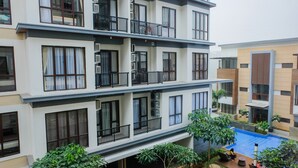 A multi-story residential building with balconies, a swimming pool, and surrounding greenery. - Highest Value 1BR Apartment at Asatti Vanya Park (Pagedangan)