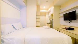 Une chambre d’hôtel dotée d’un grand lit, d’un téléviseur à écran plat fixé au mur, d’un petit bureau avec une chaise et d’une armoire intégrée.