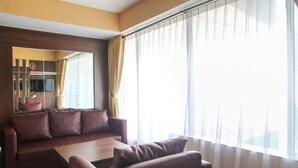 A modern living room with a sofa, armchair, and a coffee table. - Modern 2BR Grand Kamala Lagoon Apartment (Bekasi)