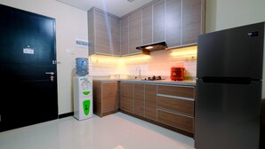 A modern kitchen with wooden cabinets, a stainless steel refrigerator, and a water dispenser. - Comfy 2BR Apartment at Nifarro Park Pasar Minggu (Jakarta)