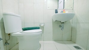 A bathroom with a toilet, sink, and mirror. - Comfy 2BR Apartment at Nifarro Park Pasar Minggu (Jakarta)