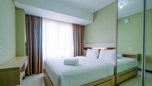 A hotel room with a bed, bedside table, and a mirror. - Comfy 2BR Apartment at Nifarro Park Pasar Minggu (Jakarta)