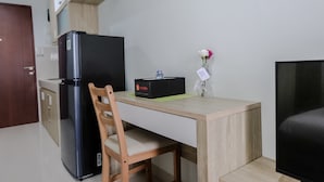 Une cuisine compacte comprenant un réfrigérateur, une table à manger en bois et une chaise. Un petit vase avec des fleurs est posé sur la table.