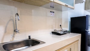 Une cuisine moderne dotée d’un évier en acier inoxydable, d’un réfrigérateur noir et d’un meuble en bois.