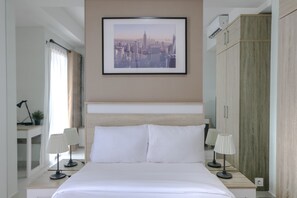 A hotel room with a large bed, two bedside tables with lamps, a framed cityscape picture on the wall, and a wardrobe. - Best Price Studio Apartment Springwood Residence (Tangerang)