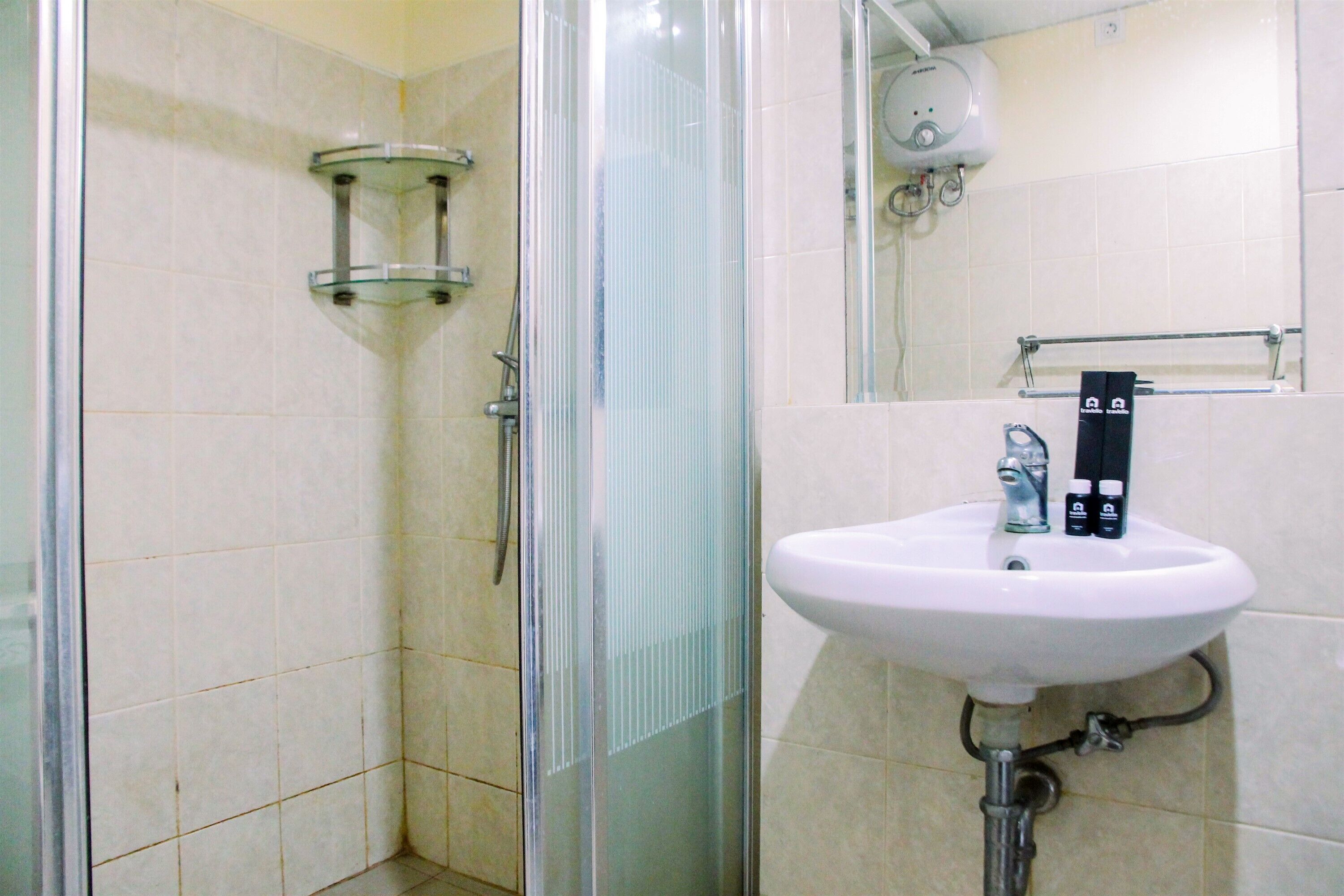A bathroom with a glass shower enclosure, a white sink with a soap dispenser, and a towel rack.