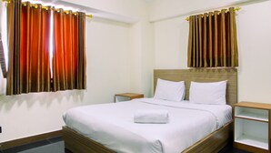 A neatly made bed with white linens, a wooden headboard, and two bedside tables with open shelves. - Modern 2BR at The Wave Epicentrum Apartment near Kuningan (Jakarta)