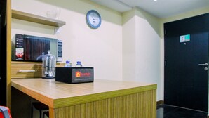 A reception area with a wooden counter, a clock, and a door with a sign. - Modern 2BR at The Wave Epicentrum Apartment near Kuningan (Jakarta)