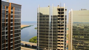 Ein Hochhaus mit Glasfassade, neben einem Fluss und einer Autobahn.