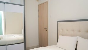 A bedroom with a bed, a wooden door, and a mirror. - 2BR Apartment at Elpis Residence near Ancol and Kemayoran (Jakarta)