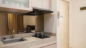 A kitchen with a stainless steel sink, a gas stove, and a modern range hood. - 2BR Apartment at Elpis Residence near Ancol and Kemayoran (Jakarta)