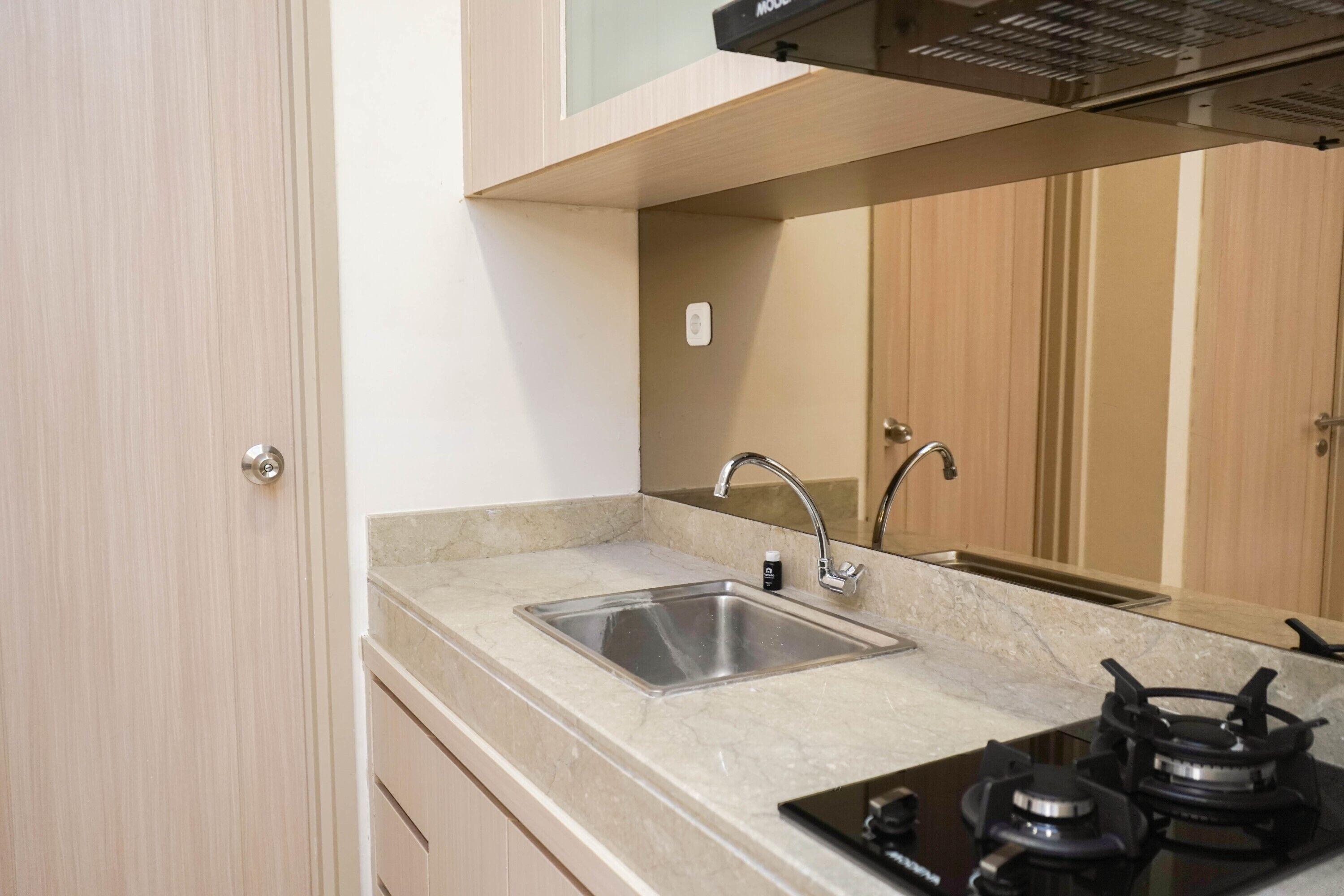 A modern kitchen with a stainless steel sink, a gas stove, and wooden cabinets.