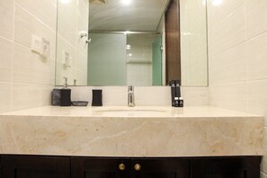 Une salle de bain avec un lavabo en marbre, un miroir et un meuble en bois foncé en dessous.