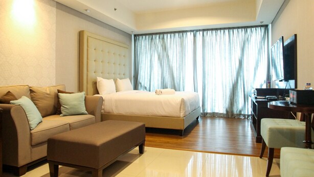 Una habitación de hotel con cama, sofá, escritorio y televisor.