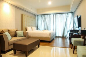 A hotel room with a bed, a sofa, a desk, and a television. - Elegant Studio Kemang Village Apartment (Jakarta)