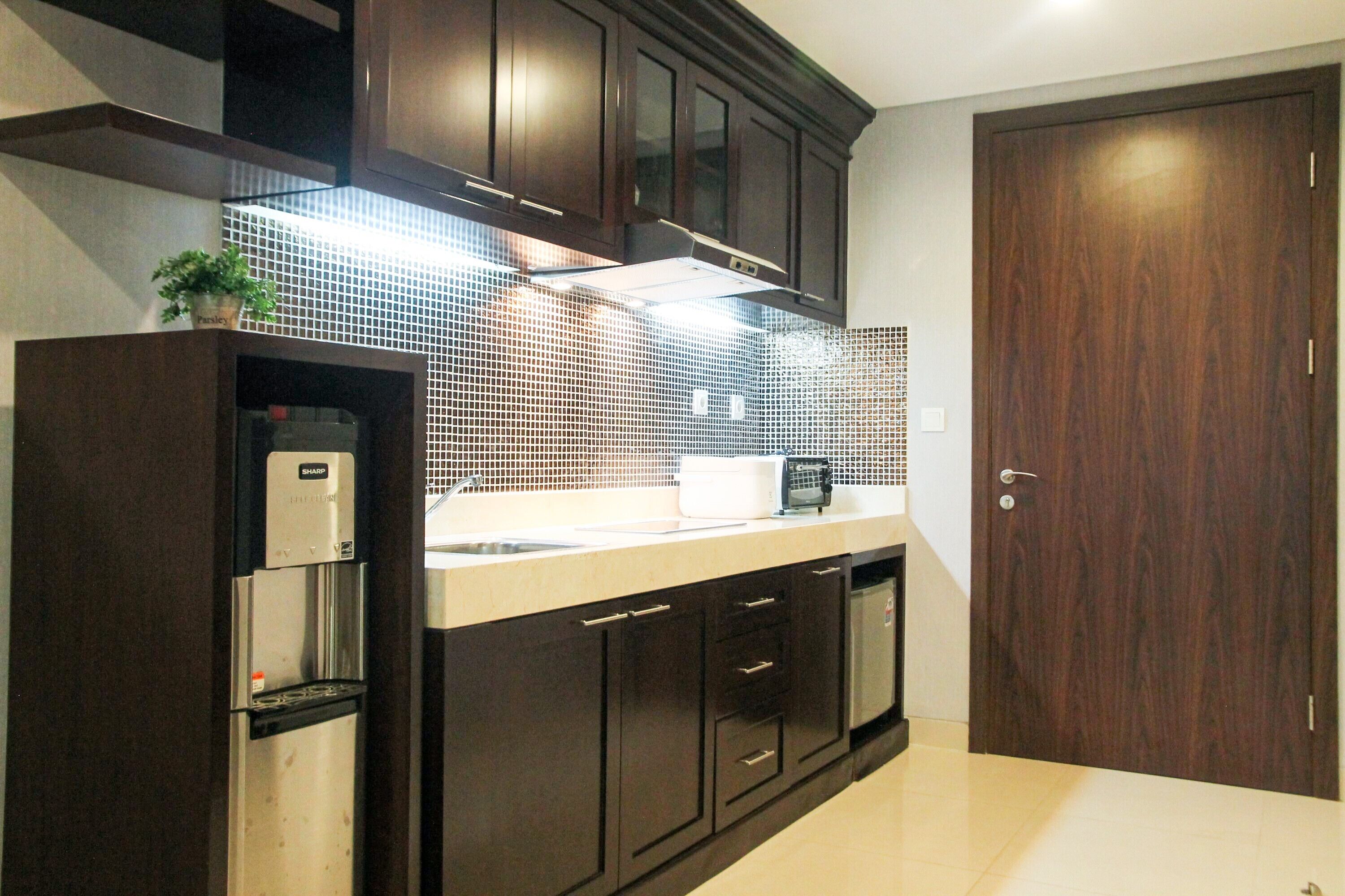 Una cocina moderna con armarios de madera oscura, un refrigerador de acero inoxidable, un microondas y un salpicadero de azulejos.