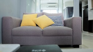 Un salón moderno con un sofá gris, dos cojines amarillos y una almohada azul y blanca con diseño zigzag.