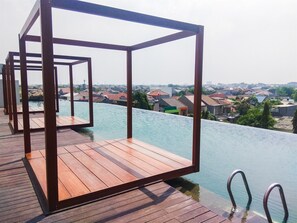 Um deck de madeira com estrutura metálica, com vista para uma piscina e uma área residencial.