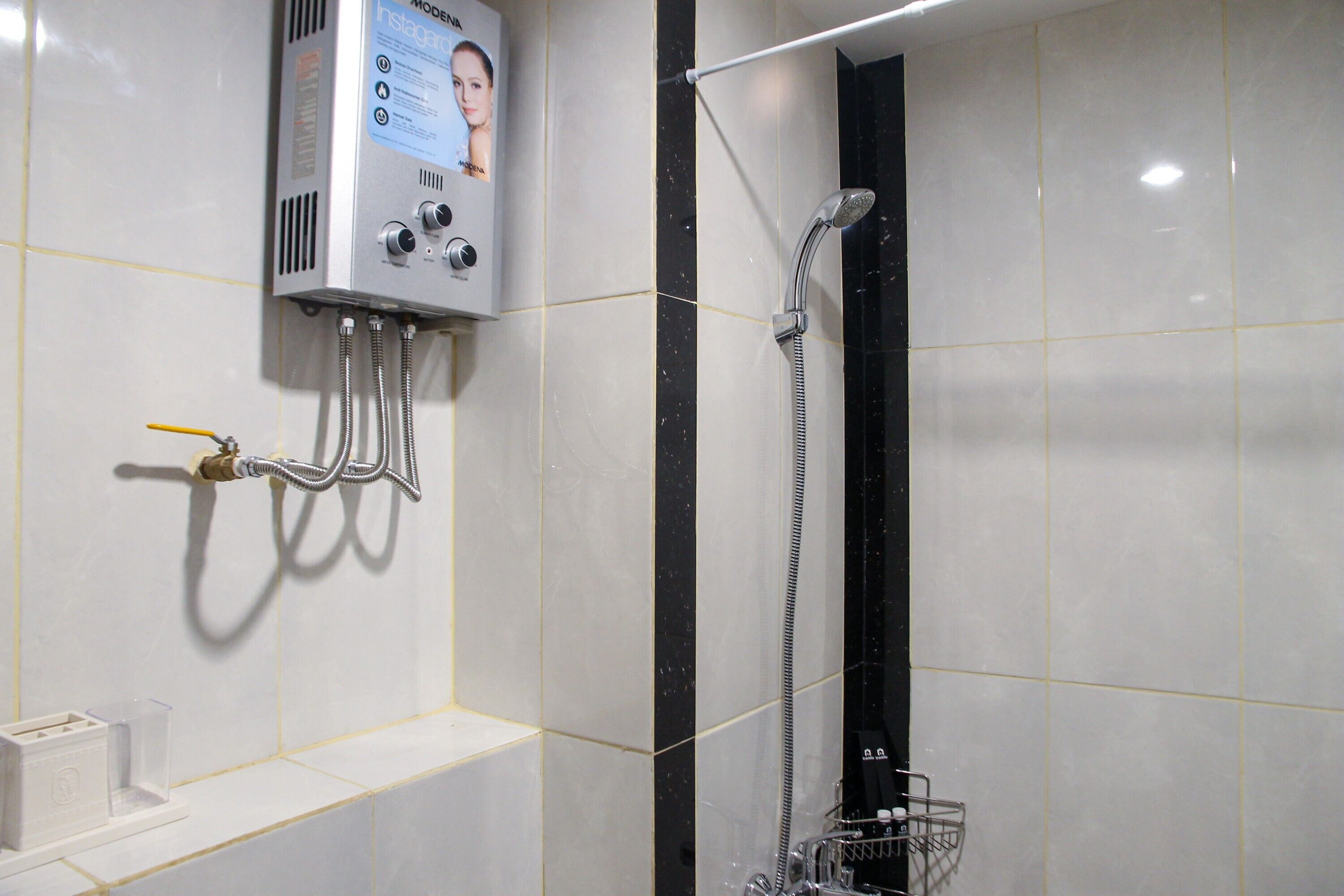 A bathroom with a wall-mounted shower unit, a handheld showerhead, and a control panel.