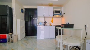 A compact kitchen with white cabinets, a microwave, and a small dining area with a glass table and chairs.